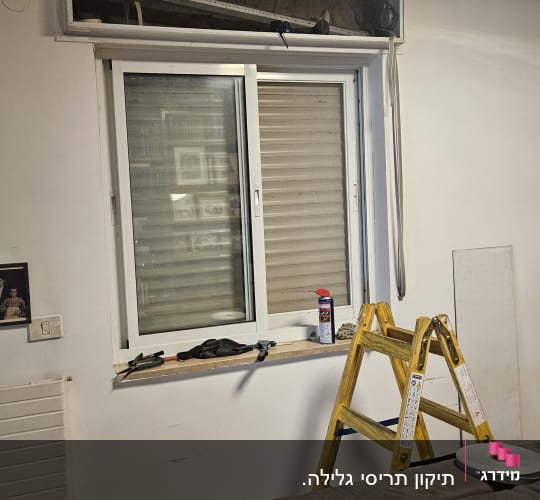 חלון עם תריסים, סולם וכלים על אדן החלון
